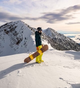 Snowboarder on a ridge at Kicking Horse Mountain Resort above a cloud-filled valley, Golden BC