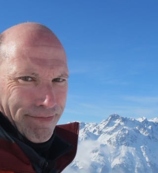 Patrick Thorne, editor of InTheSnow, in front of snow-capped Alpine peaks