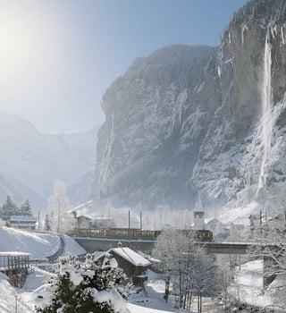 Train crossing the Lauterbrunnen valley beneath the frozen Staubbach Falls in winter