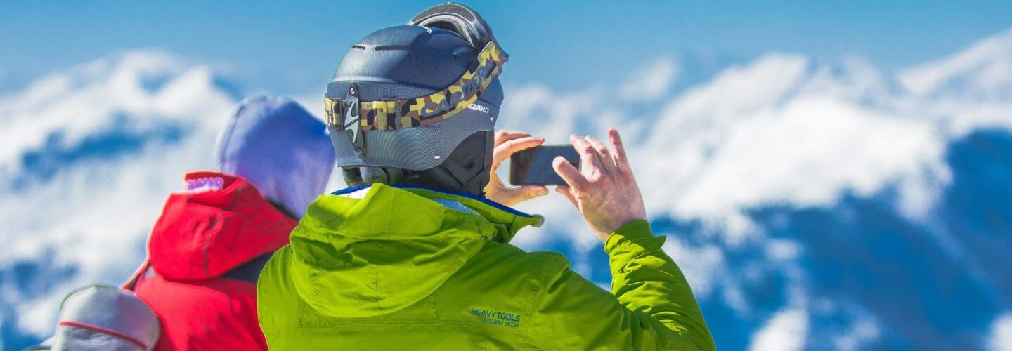 man in green jacket and gray helmet holding phone standing 163168