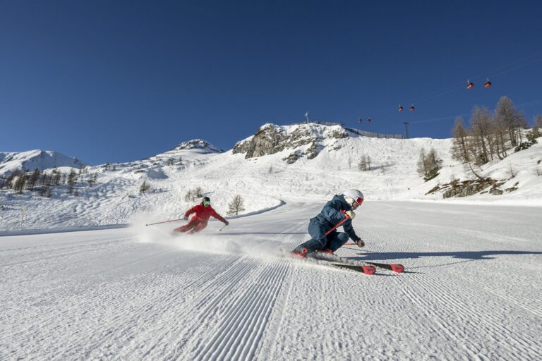 Two skiers carving fresh corduroy in Zauchensee