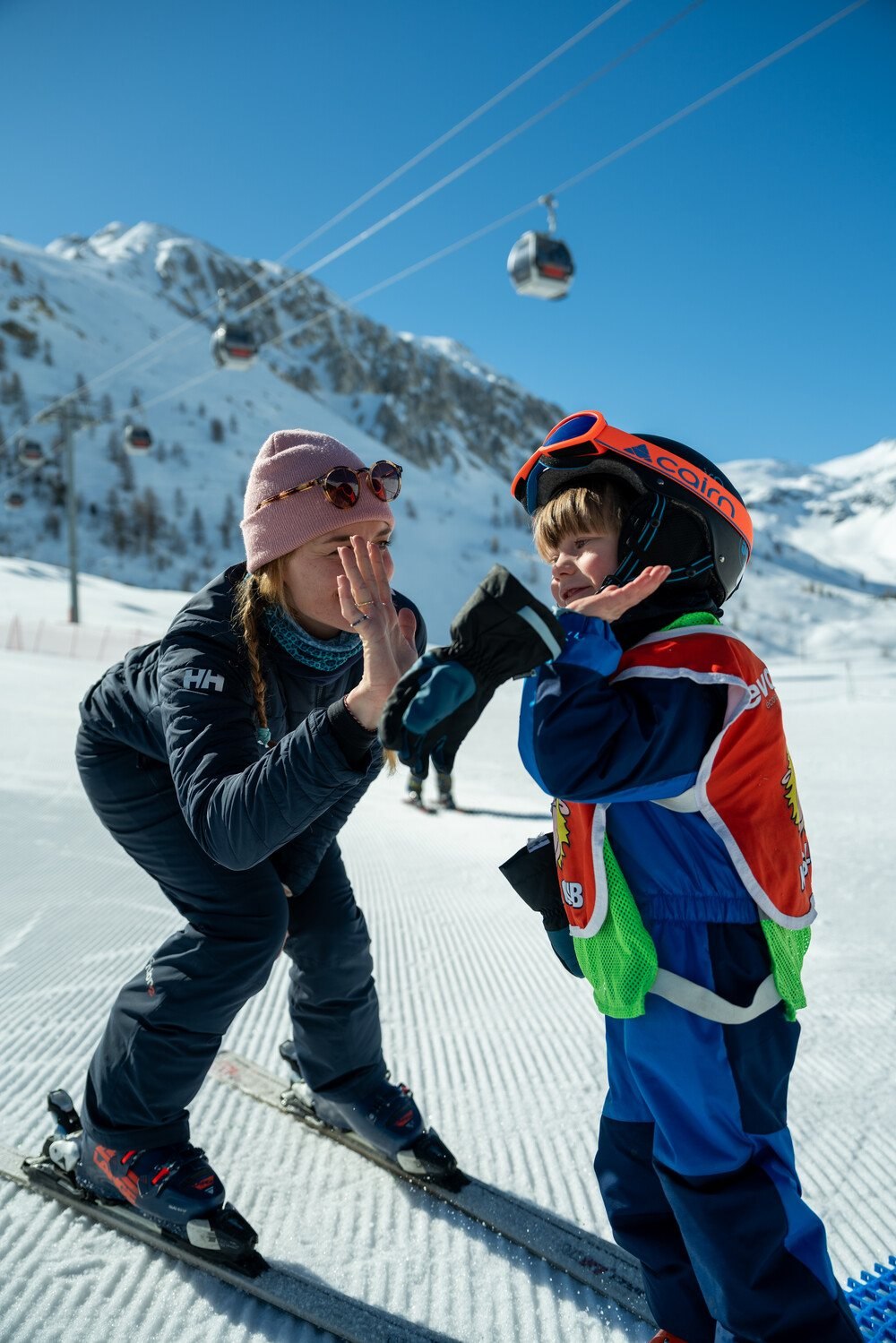 Evolution 2 ski instructor giving a young child a high five on the nursery slope in Tignes