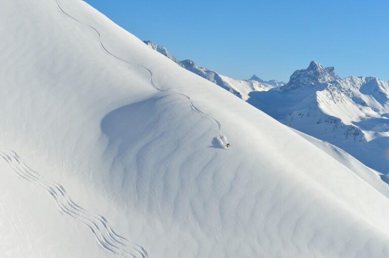 Freerider carving fresh tracks down an untouched powder slope at Ski Arlberg