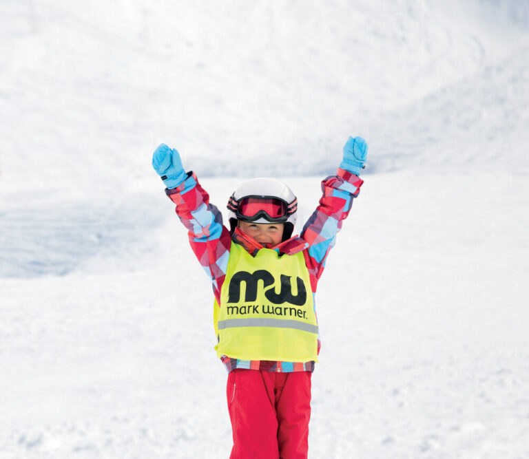 Smiling child in a Mark Warner ski school bib on the slopes