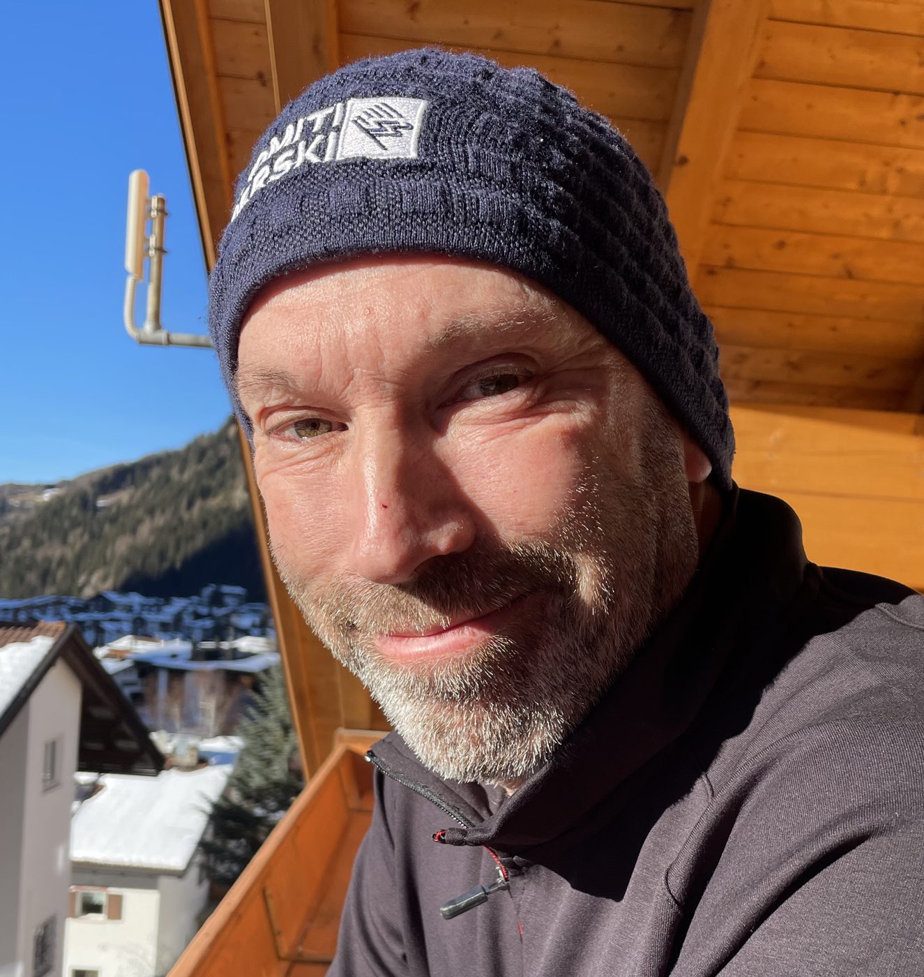 Patrick Thorne smiling in the sunshine on a wooden chalet balcony