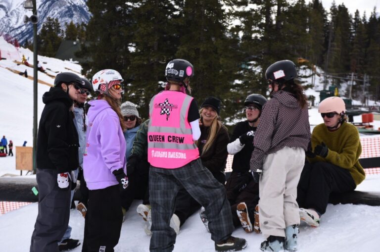 Quay Queens group with a member in a pink 'Queen Crew' safety vest at Norquay Ski Resort, Banff