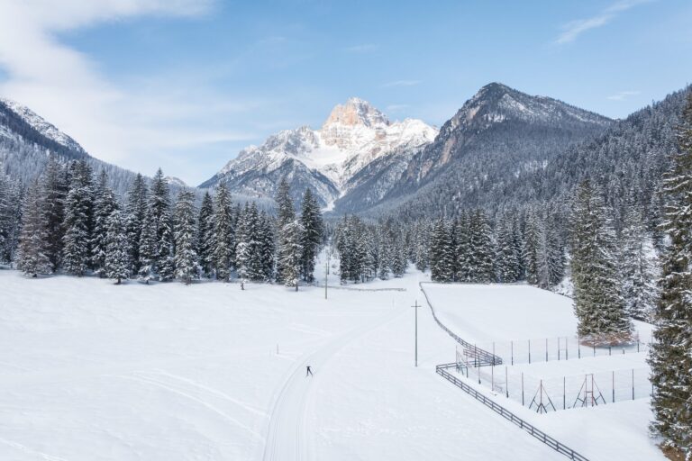 Aerial view of a lone cross-country skier on a snowy valley trail in the 3 Zinnen Dolomites
