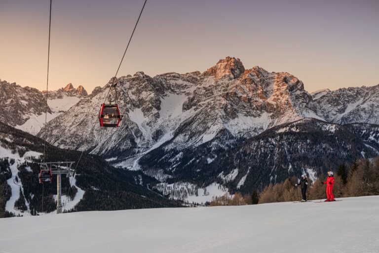 Red gondola gliding above the piste as the Dolomites glow at sunset in the 3 Zinnen Dolomites