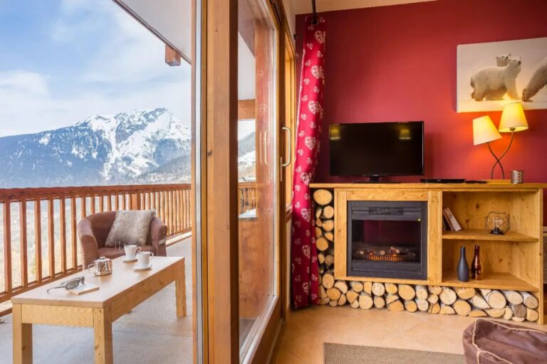 Living area with log fire and mountain-view balcony in an Etoile des Cîmes apartment, Sainte Foy