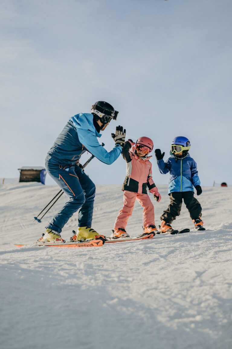 Ski instructor high-fiving two young children on a beginner slope in Gitschberg Jochtal