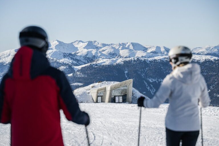 Two skiers looking towards the Messner Mountain Museum Corones at the Kronplatz summit