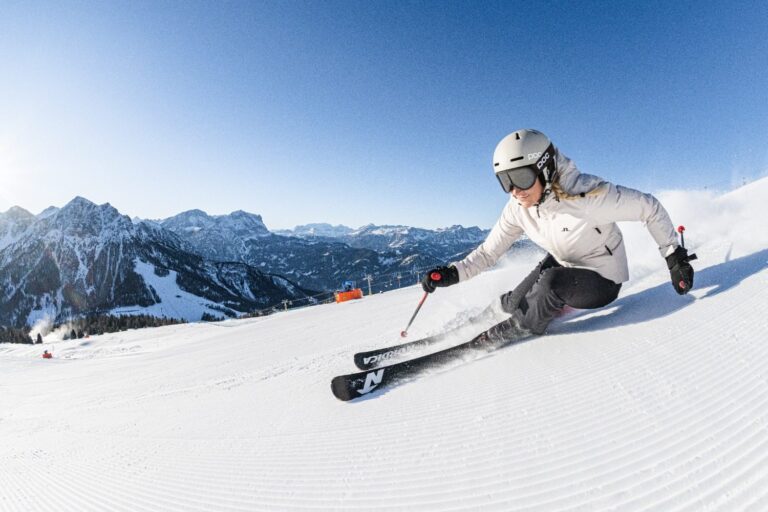 Skier carving a perfectly groomed piste on Kronplatz with Dolomite peaks behind