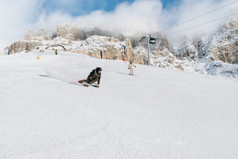 Skier carving down a freshly groomed piste in Latemar Dolomites towards the Latemar peaks