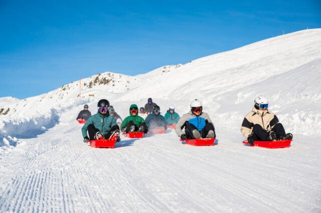 Group sledging on the Roc'n Bob run in Les Menuires on a sunny day
