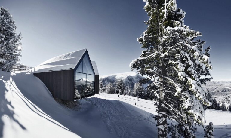 The modern Oberholz mountain hut among snowy trees in Latemar Dolomites
