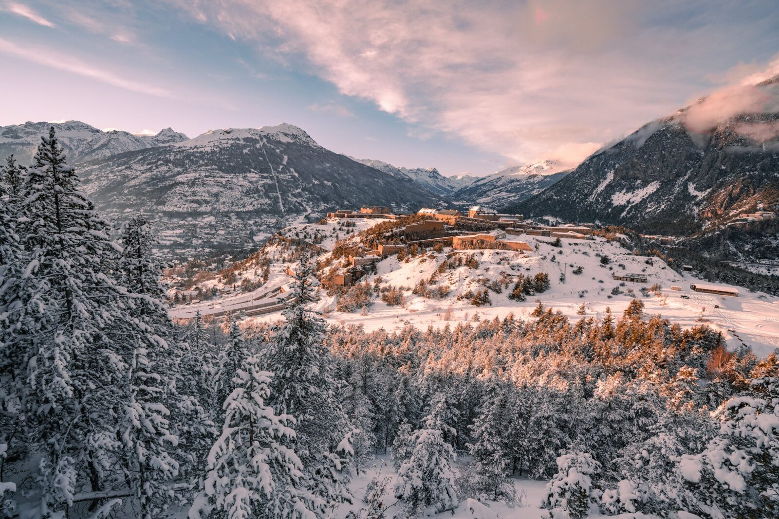 Snow-covered forest and historic fortifications above the valley at Serre Chevalier, French Alps