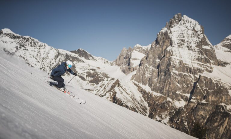 Skier carving a steep piste in Sterzing-Ratschings-Gossensass in front of a dramatic rocky peak