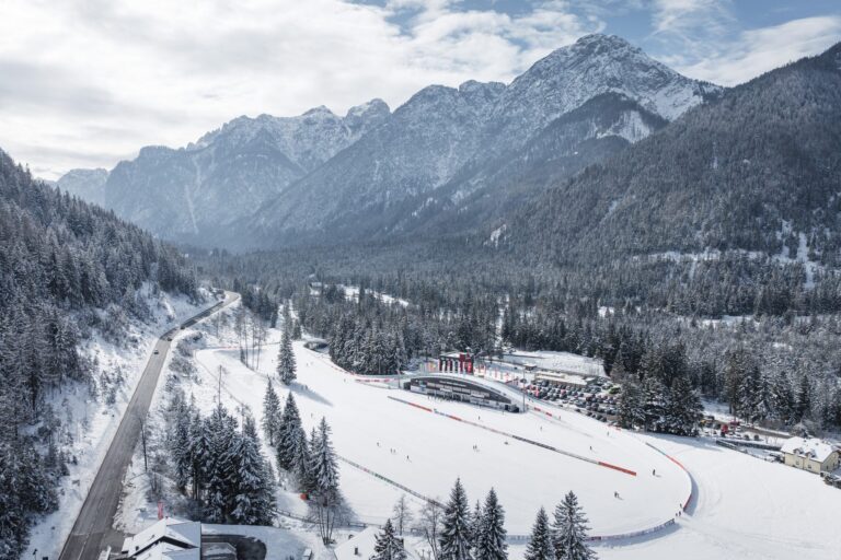 Aerial view of the Toblach Nordic Arena surrounded by snowy forest and mountains
